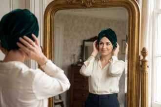 Femme élégante ajustant un turban en velours devant un miroir ancien