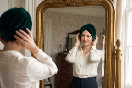 Femme élégante ajustant un turban en velours devant un miroir ancien